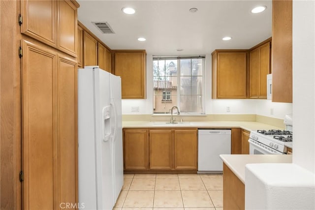kitchen featuring recessed lighting, white appliances, visible vents, brown cabinetry, and a sink