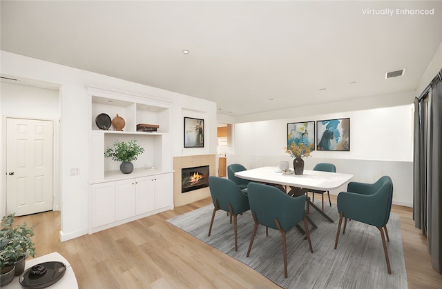 dining space featuring light wood-style flooring, a fireplace, and visible vents
