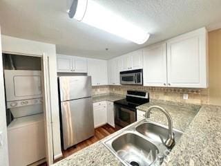838 Pine Ave Unit 510, Long Beach, CA 90813 - kitchen featuring stainless steel appliances, estacked washer and dryer, a sink, white cabinetry, and backsplash