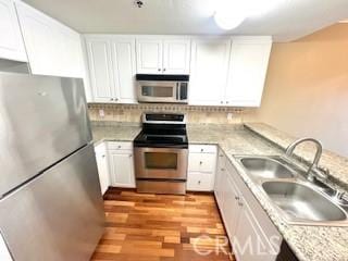 838 Pine Ave Unit 510, Long Beach, CA 90813 - kitchen with appliances with stainless steel finishes, a sink, light countertops, light wood finished floors, and white cabinets