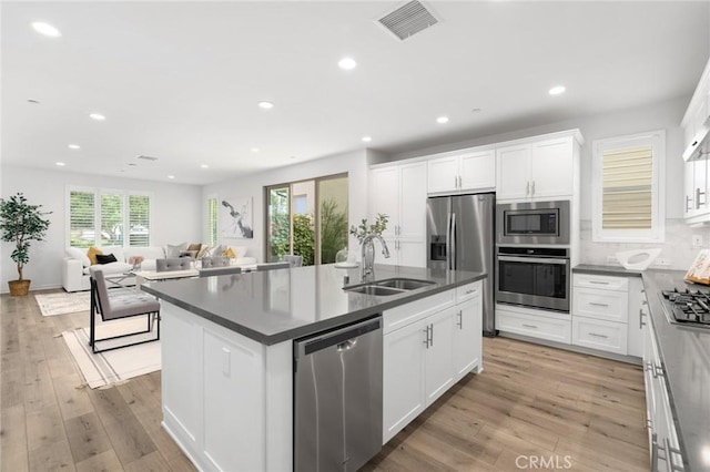 148 Modjeska, Irvine, CA 92618 - kitchen with stainless steel appliances, a kitchen island with sink, dark countertops, recessed lighting, and white cabinetry