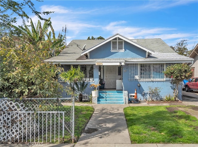 bungalow-style house with stucco siding, covered porch, a front lawn, and fence