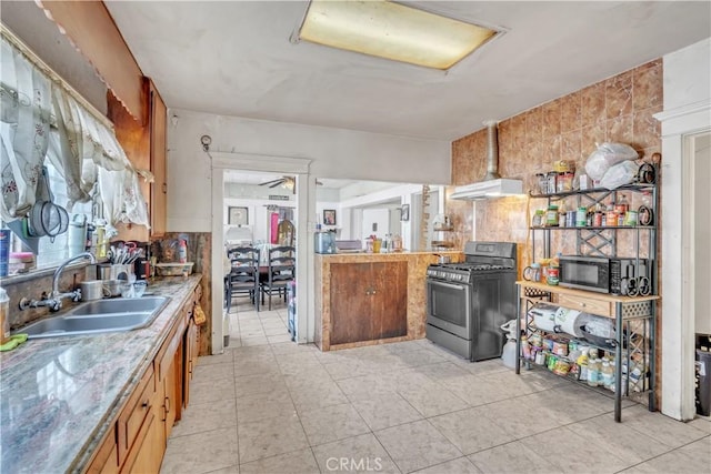 kitchen featuring brown cabinets, a sink, under cabinet range hood, light countertops, and stainless steel gas range