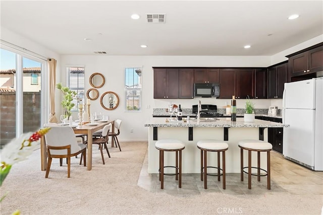 1437 Girona Dr, Pomona, CA 91766 - kitchen featuring freestanding refrigerator, black microwave, stove, a kitchen breakfast bar, and plenty of natural light