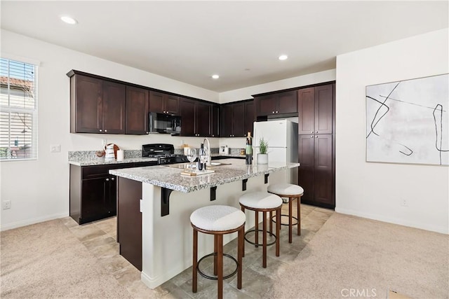 1437 Girona Dr, Pomona, CA 91766 - kitchen with black microwave, range with gas cooktop, a kitchen breakfast bar, light stone counters, and a kitchen island with sink