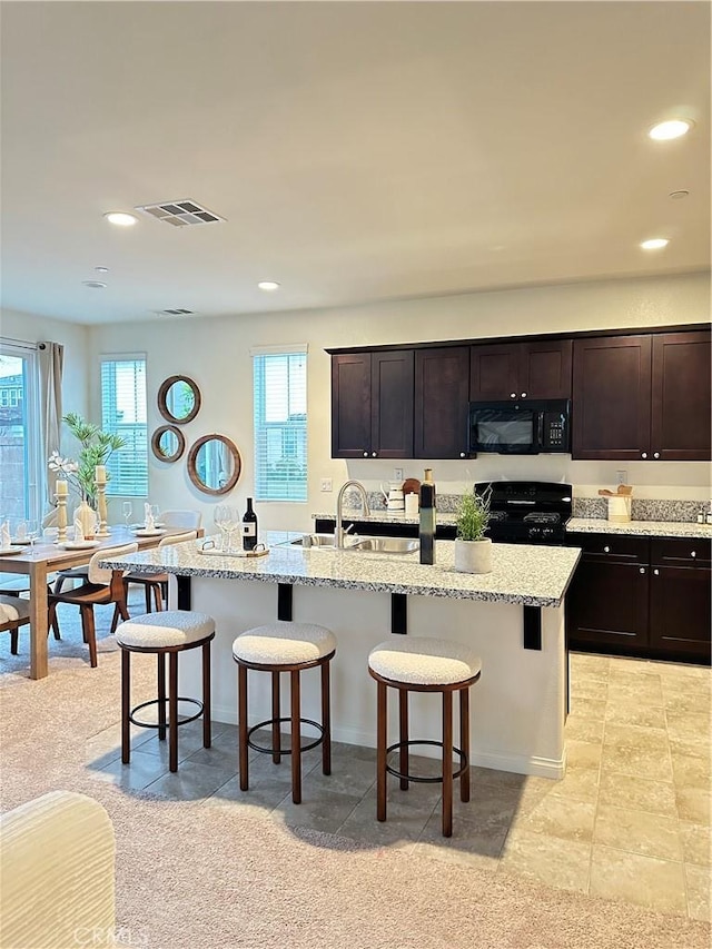 1437 Girona Dr, Pomona, CA 91766 - kitchen featuring black appliances, a breakfast bar, healthy amount of natural light, recessed lighting, and light stone counters