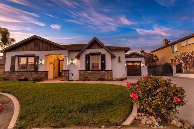view of front of home with a gate, concrete driveway, stucco siding, an attached garage, and a front lawn