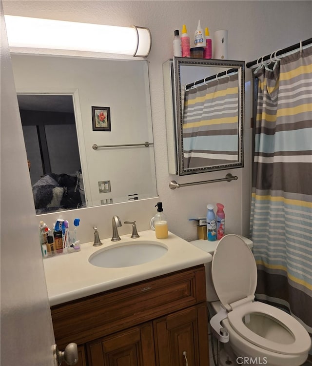 bathroom featuring a shower with shower curtain, toilet, and vanity