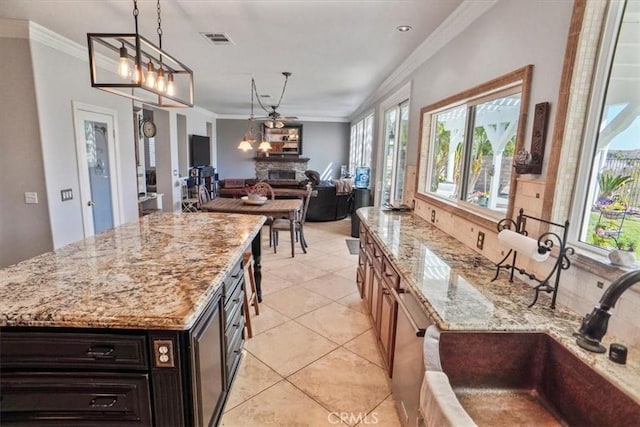 29086 Madrid Pl, Castaic, CA 91384 - kitchen featuring visible vents, a sink, light stone counters, a glass covered fireplace, and ornamental molding