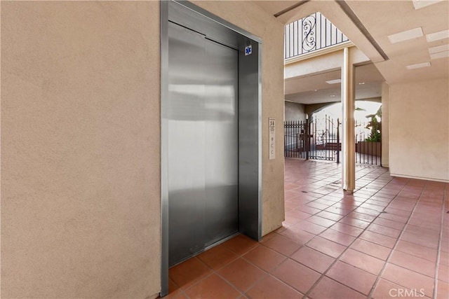 hall with elevator and tile patterned floors