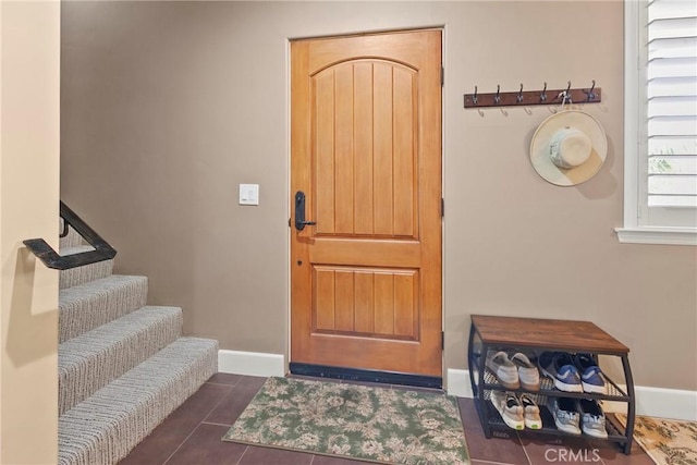 foyer with dark tile patterned floors and baseboards