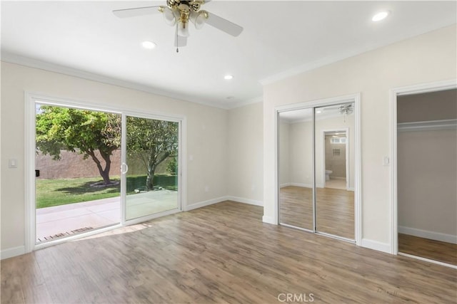 unfurnished bedroom with two closets, ornamental molding, access to exterior, wood finished floors, and baseboards