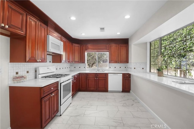 kitchen with a healthy amount of sunlight, recessed lighting, white appliances, and marble finish floor