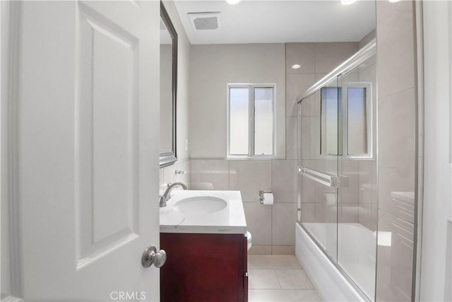 full bathroom with vanity, tile patterned flooring, visible vents, enclosed tub / shower combo, and tile walls