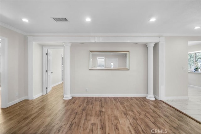 interior space featuring baseboards, ornamental molding, visible vents, ornate columns, and wood finished floors