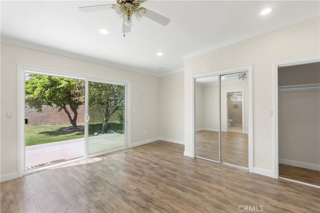 unfurnished bedroom featuring baseboards, two closets, crown molding, wood finished floors, and access to outside