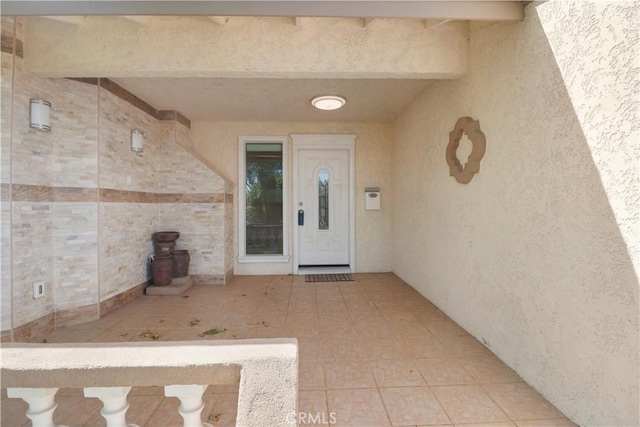 view of exterior entry with a patio and stucco siding