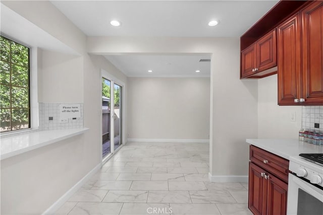 kitchen with white gas range, tasteful backsplash, marble finish floor, light countertops, and baseboards