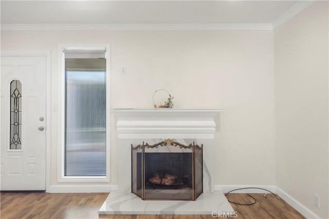 interior details with a high end fireplace, baseboards, crown molding, and wood finished floors