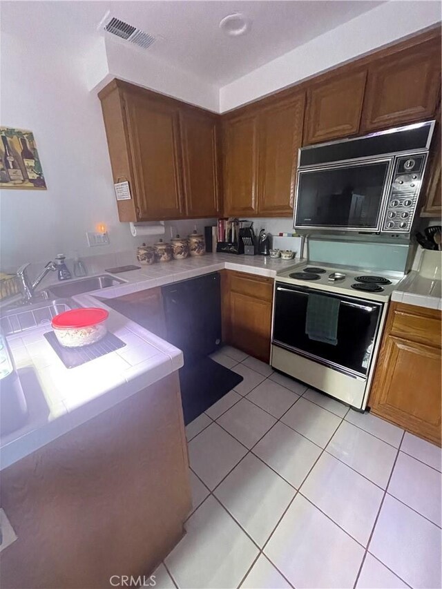 18269 Sanmian Ct, Fountain Valley, CA 92708 - kitchen featuring black microwave, white electric range, tile countertops, light tile patterned floors, and brown cabinetry