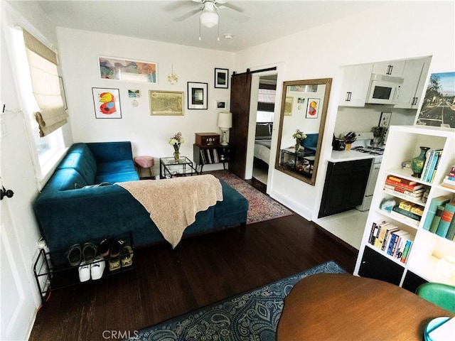 living area with a barn door, a ceiling fan, and light wood-type flooring
