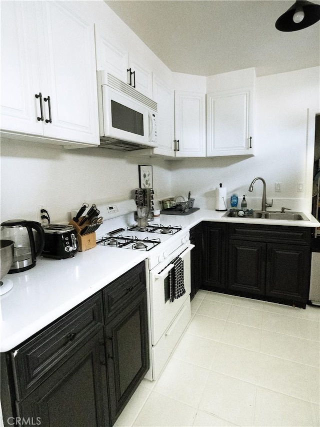 kitchen with light countertops, dark cabinetry, white cabinets, white appliances, and a sink