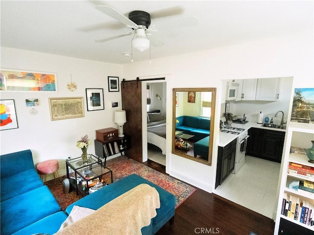 living room featuring a barn door, light wood-type flooring, and a ceiling fan