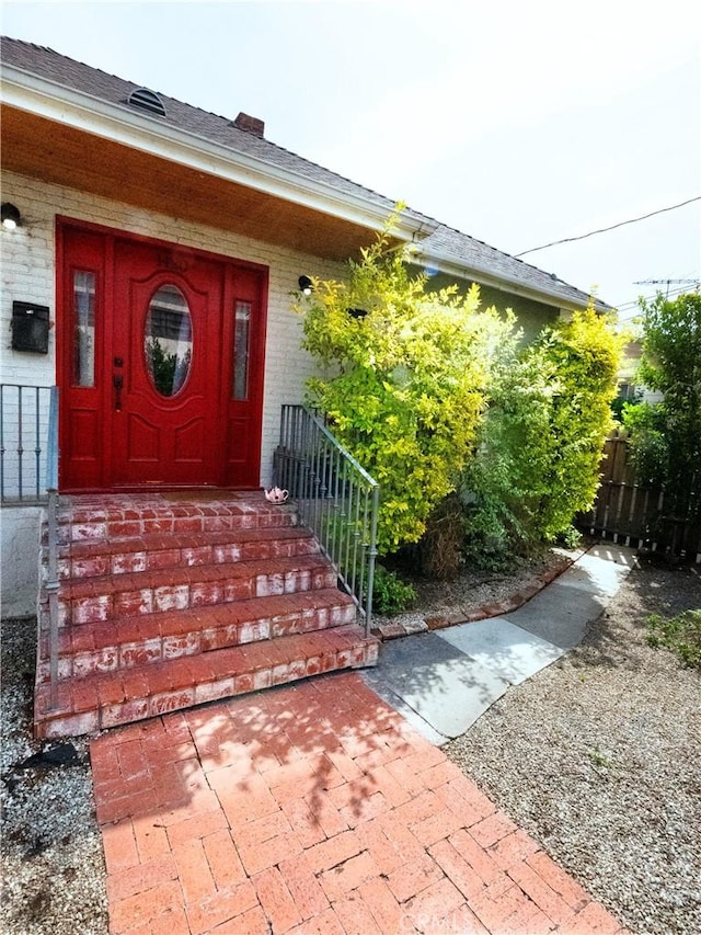 property entrance with brick siding and fence
