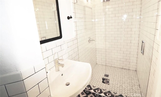 full bath featuring tile walls, a stall shower, and a sink