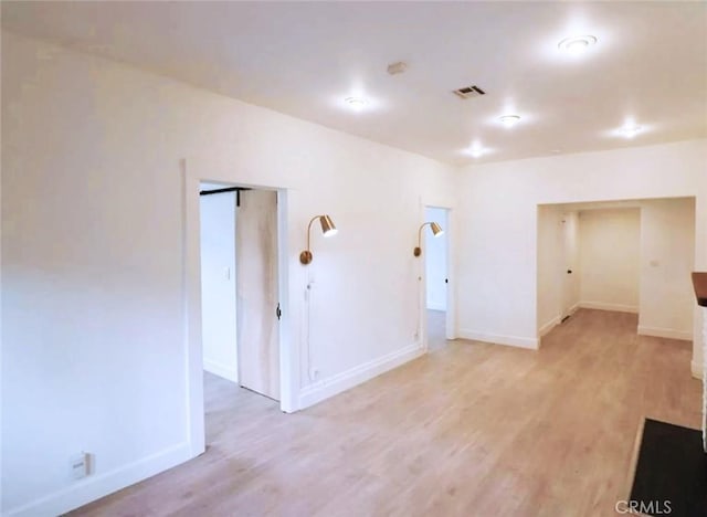 unfurnished room featuring visible vents, light wood-style flooring, and baseboards