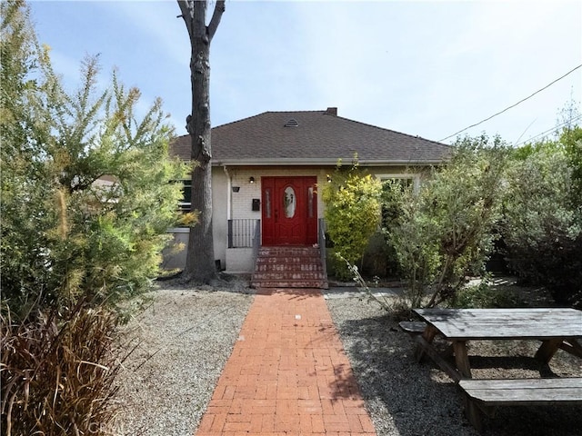 bungalow featuring brick siding and a shingled roof