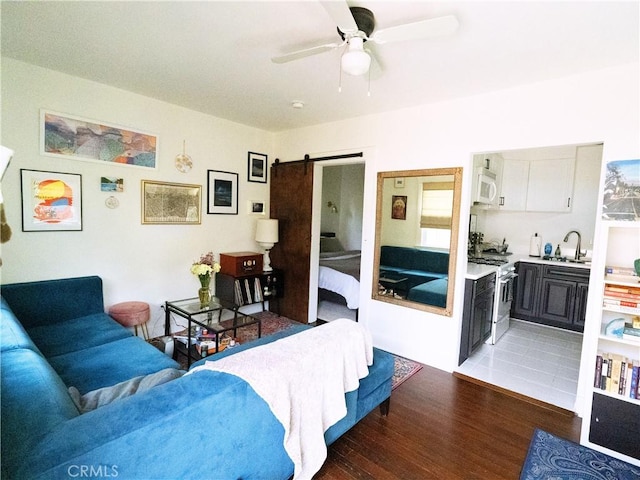living area featuring a barn door, light wood-style flooring, and a ceiling fan