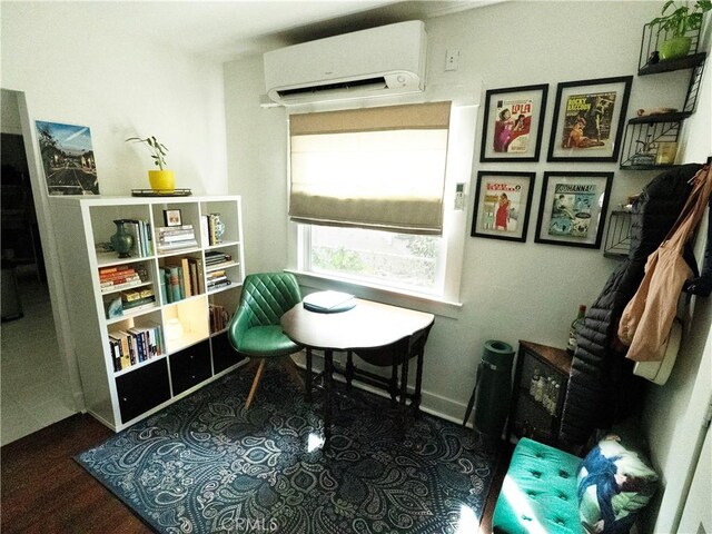 living area featuring an AC wall unit and baseboards