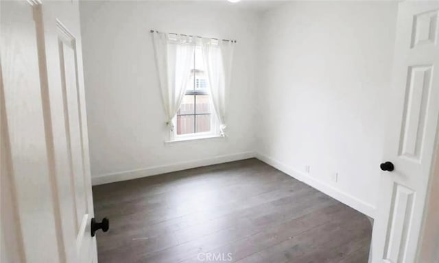 spare room featuring baseboards and wood finished floors
