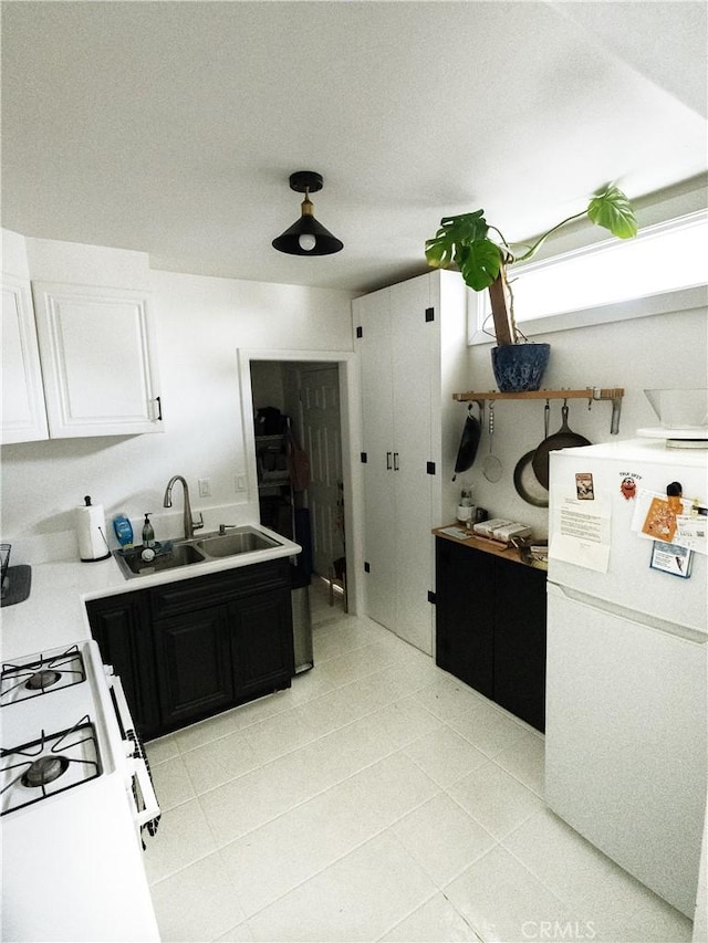 kitchen with a sink, dark cabinetry, white appliances, white cabinets, and light countertops
