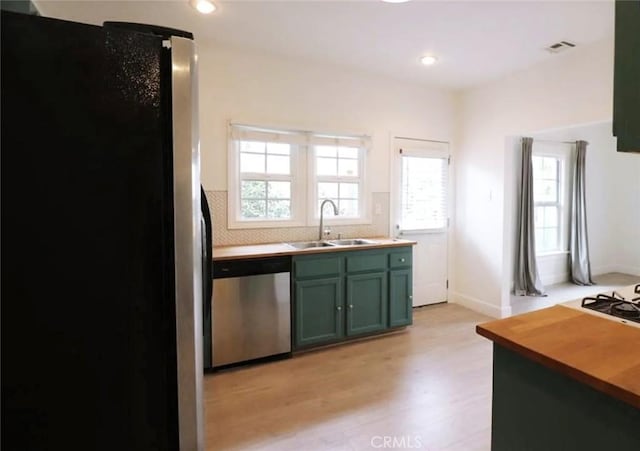 kitchen featuring light wood-type flooring, visible vents, a sink, stainless steel appliances, and green cabinetry