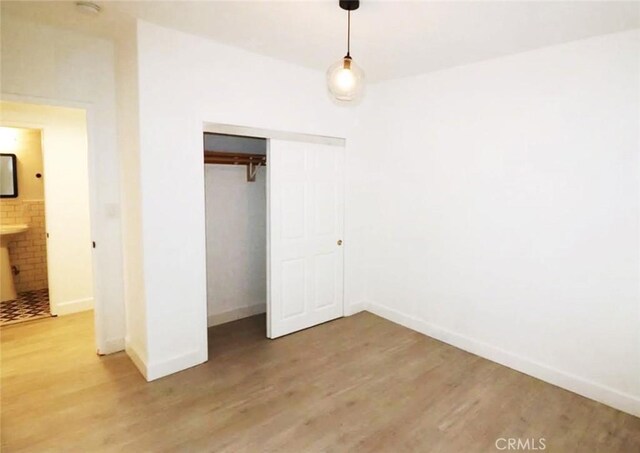 unfurnished bedroom featuring a closet, baseboards, and wood finished floors
