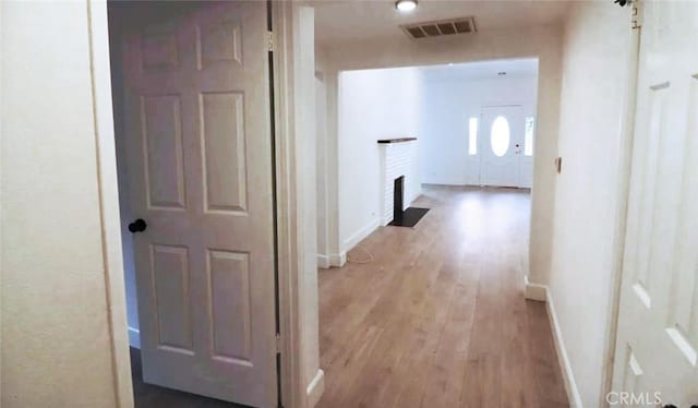 hallway with visible vents, baseboards, and light wood finished floors