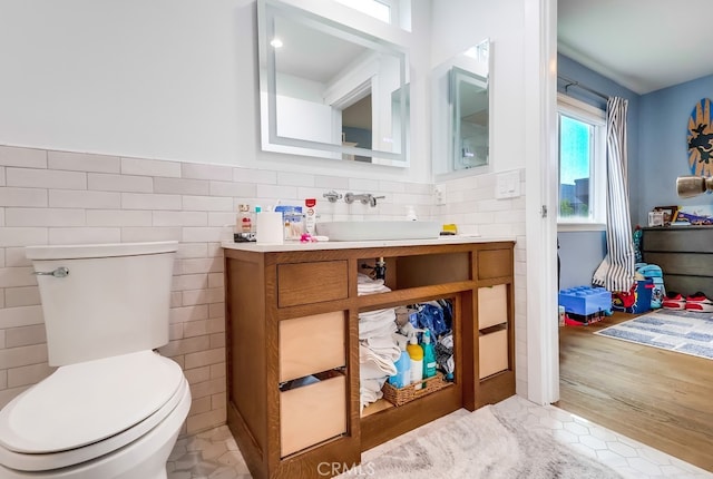half bath featuring tile patterned flooring, toilet, tile walls, and vanity