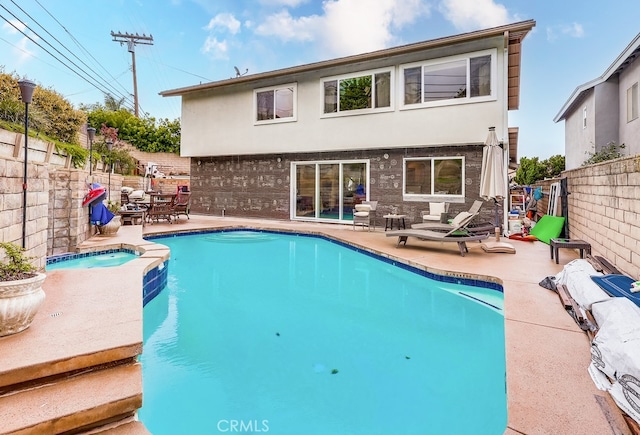 back of house with a patio area, stucco siding, a pool with connected hot tub, and a fenced backyard