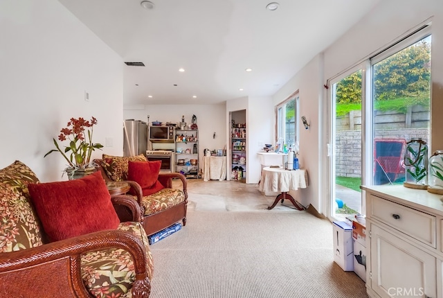 living room with recessed lighting, visible vents, and light carpet