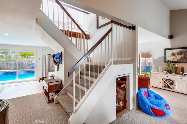 stairs featuring a high ceiling and carpet