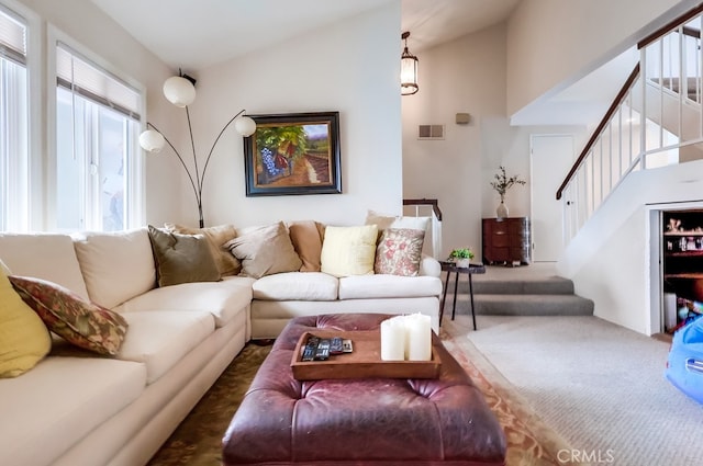 living area with stairway, lofted ceiling, visible vents, and carpet flooring