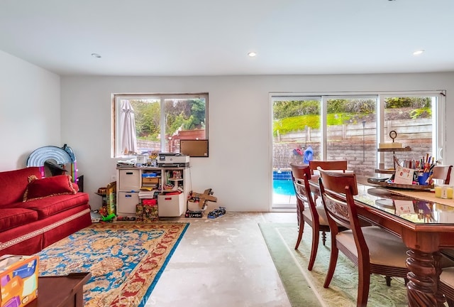 living room featuring plenty of natural light, recessed lighting, and unfinished concrete flooring