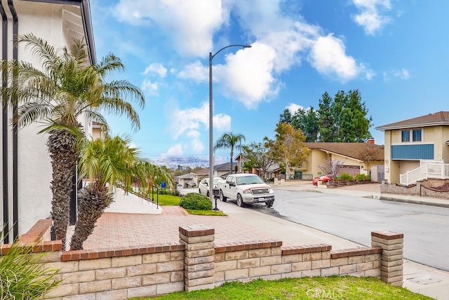 view of street with sidewalks, curbs, a residential view, and street lights