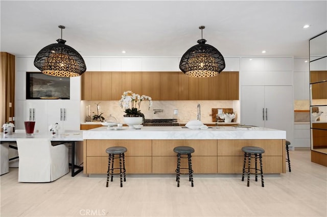 2914 Ocean Blvd, Corona Del Mar, CA 92625 - kitchen with modern cabinets, a breakfast bar, backsplash, an inviting chandelier, and hanging light fixtures