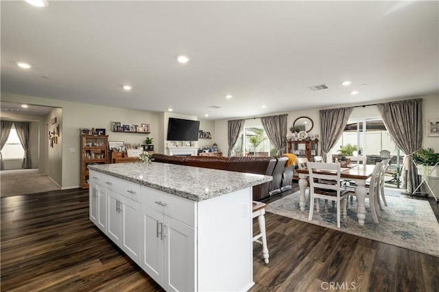 29068 Aubrey Cir, Winchester, CA 92596 - kitchen with a kitchen island, white cabinetry, light stone countertops, dark wood finished floors, and visible vents