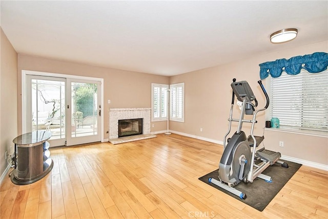 exercise room featuring a fireplace, plenty of natural light, wood finished floors, and baseboards