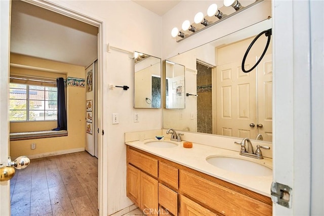 full bathroom featuring a sink, baseboards, wood finished floors, and double vanity