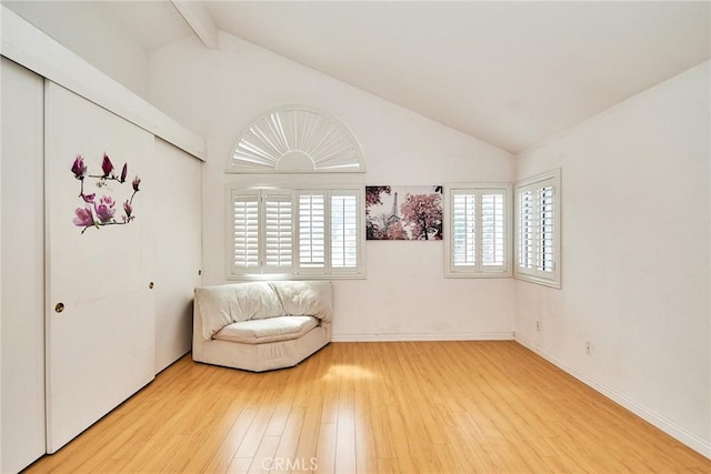 unfurnished room with lofted ceiling with beams, light wood-style flooring, and baseboards